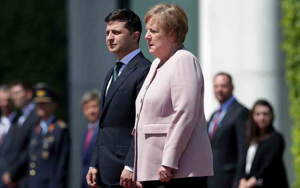 La canciller alemana Angela Merkel, visiblemente temblorosa, y el presidente ucraniano Volodymyr Zelenskiy escuchan los himnos en una recepción en Berlín / Foto: AP. 