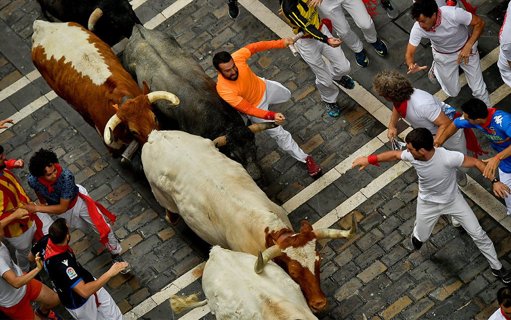 Corredores pasan junto a los toros de la ganadería José Escolar durante el tercer encierro de las fiestas de San Fermín, en Pamplona, España / Foto: AP. 
