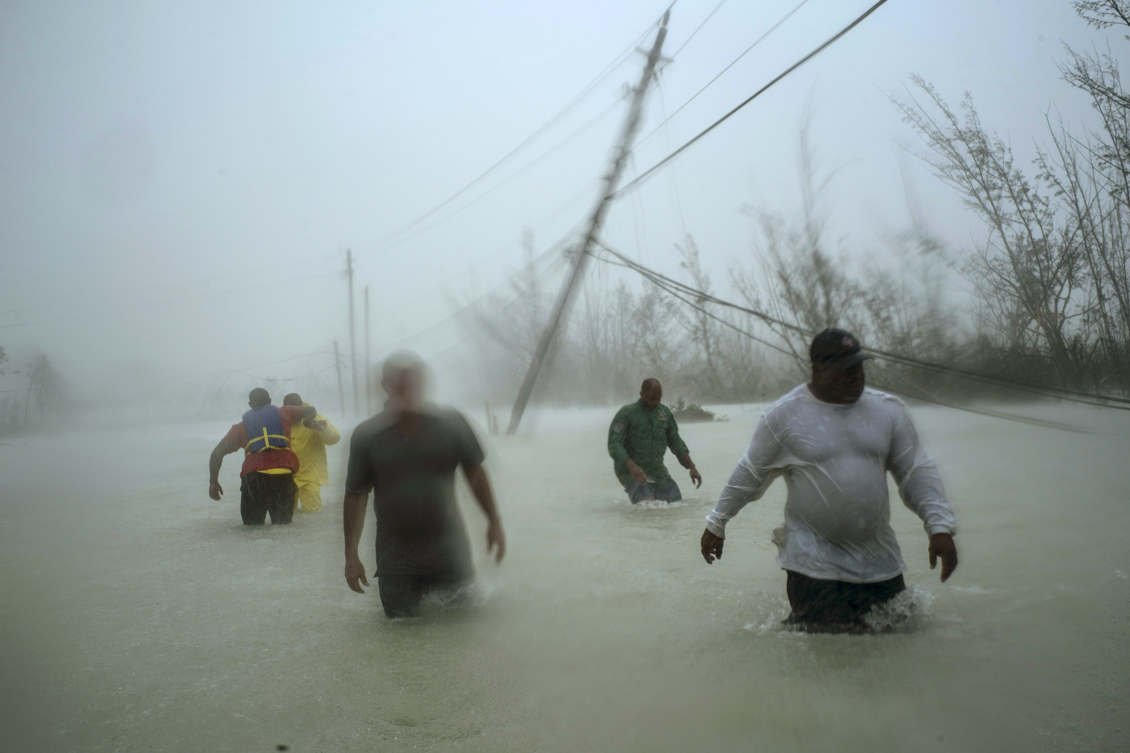 Voluntarios caminan por una calle inundada y bajo el viento y la lluvia del huracán Dorian mientras tratan de rescatar familias cerca del puente Causarina en Freeport, Gran Bahama, el martes 3 de septiembre de 2019. (Foto AP)