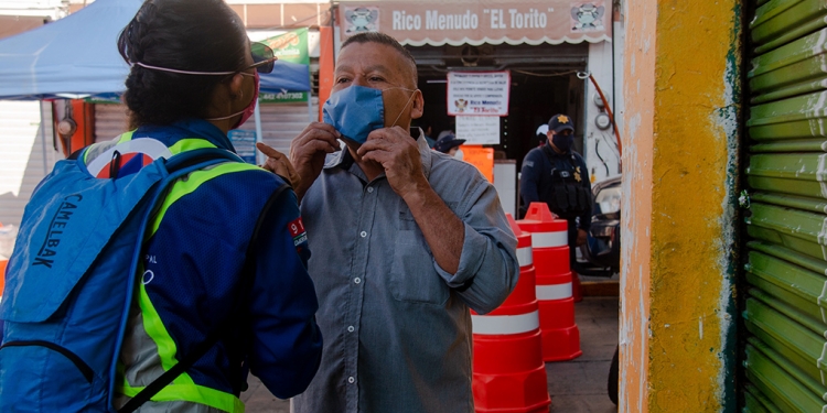 Personal de Protección Civil instalado en tianguis y mercados enseña a los ciudadanos a colocarse el tapabocas. Foto Selene Ugalde