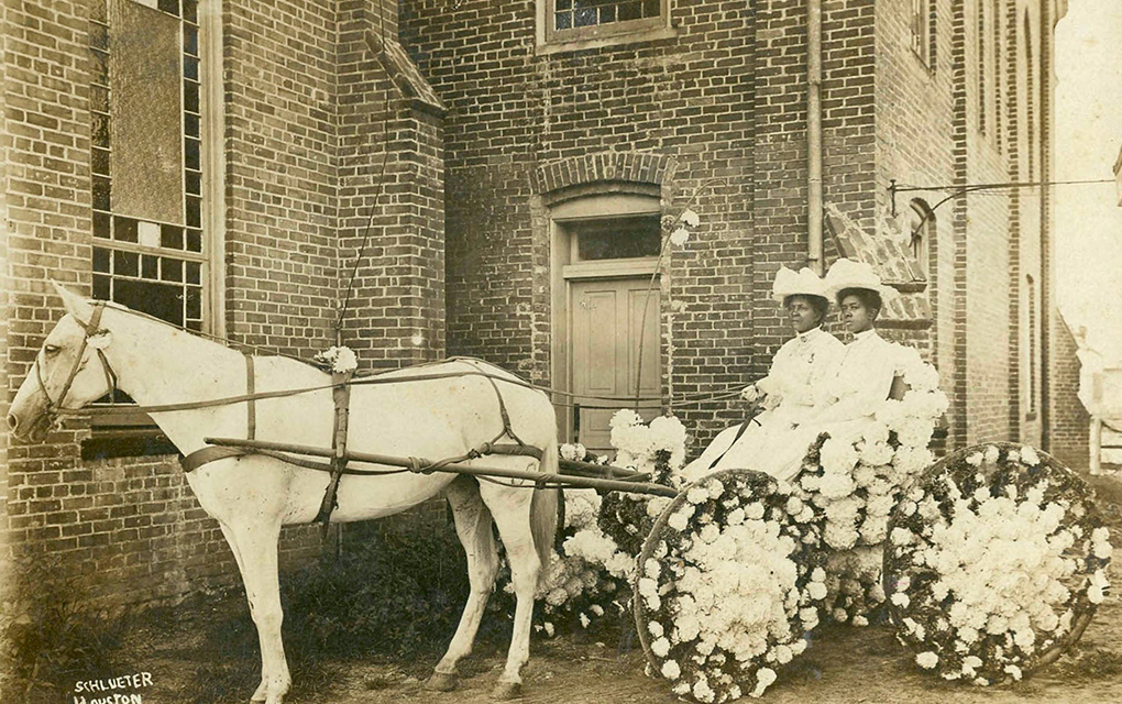 Una fotografía de 1908 de dos mujeres en Texas sentadas en un carro alegórico decorado con flores para la celebración anual del Día de la Libertad, estacionado frente a la iglesia bautista antioquia ubicada en el vecindario de Fourth Ward en Houston. / Foto: The New York Times
