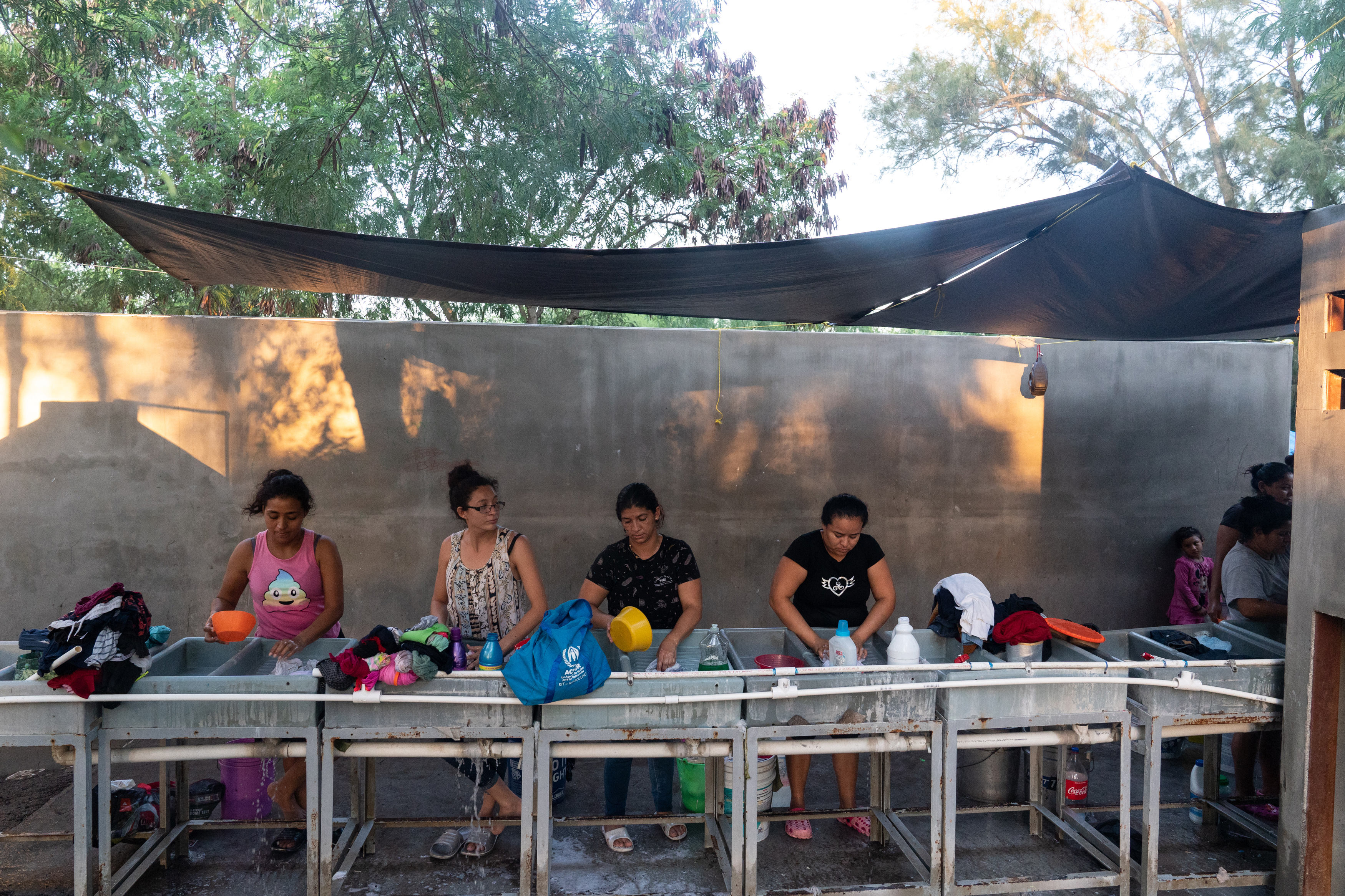 Mujeres migrantes lavan ropa en un campamento de refugiados en Matamoros. (The New york times)