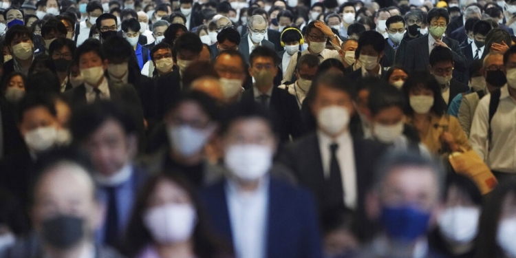 Centenares de pasajeros con mascarillas caminan por el pasillo de una estación de transporte colectivo durante una hora pico en Tokio. (AP)