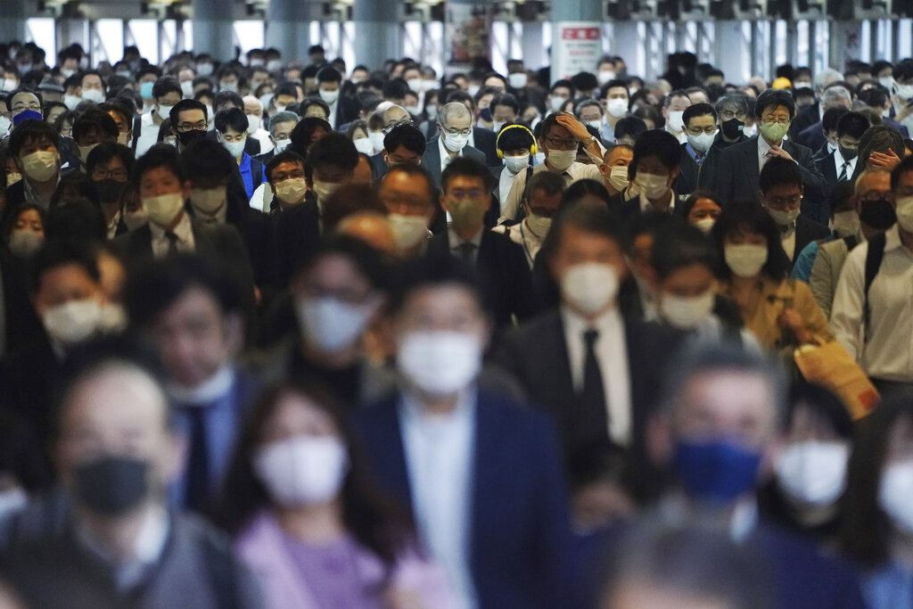 Centenares de pasajeros con mascarillas caminan por el pasillo de una estación de transporte colectivo durante una hora pico en Tokio. (AP)