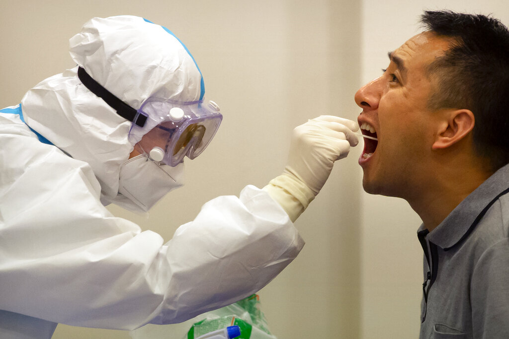 Personal médico le realiza una prueba de coronavirus a un hombre en Hainan, China. AP