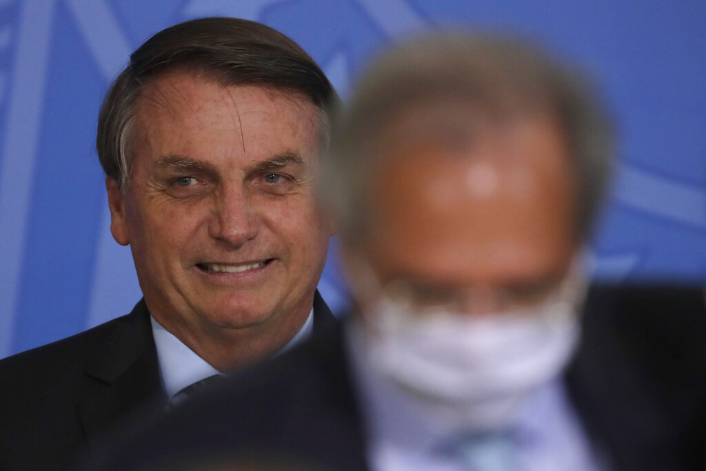 Bolsonaro sonríe detrás de su ministro de Economía Paulo Guedes durante una ceremonia en el palacio presidencial de Planalto, en Brasilia, el jueves 26 de noviembre de 2020. (AP)
