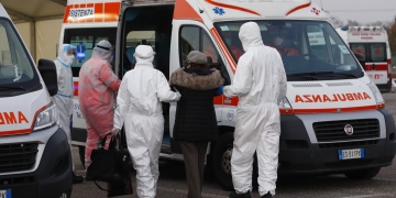 Médicos ayudan a una anciana a subir a una ambulancia en un puesto de control al aire libre de Milán. (AP)