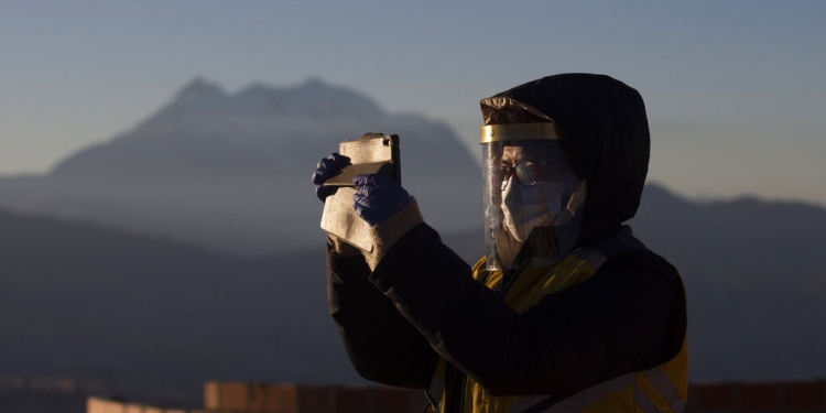 Un empleado municipal con una máscara facial en medio de la propagación del nuevo coronavirus se toma una selfie con los primeros rayos de sol durante un ritual de año nuevo en el Mirador Jach'a Apacheta de Munaypata, en La Paz, Bolivia. (AP)