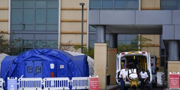 Fotografía del jueves 17 de diciembre de 2020 de trabajadores médicos retirando una camilla de una ambulancia cerca de carpas médicas erigidas afuera de la sala de emergencias del UCI Medical Center en Irvine, California. (AP)