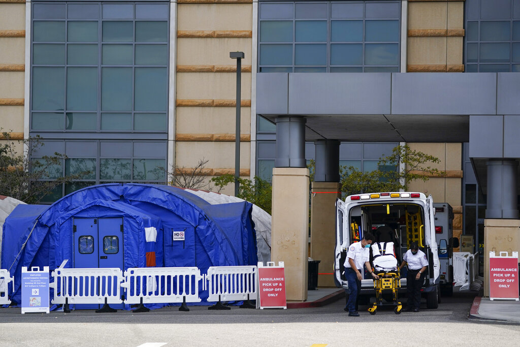 Fotografía del jueves 17 de diciembre de 2020 de trabajadores médicos retirando una camilla de una ambulancia cerca de carpas médicas erigidas afuera de la sala de emergencias del UCI Medical Center en Irvine, California. (AP)