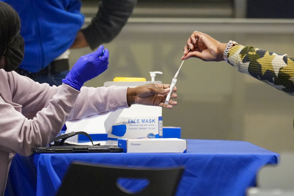 un viajero coloca un hisopo dentro de un tubo de ensayo después de tomar una muestra para una prueba de COVID-19 en un centro móvil de pruebas del sistema de salud de la ciudad de Nueva York, en Penn Station. (AP)