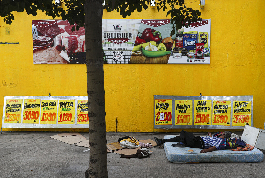 Un indigente duerme en un colchón en una acera cerca de una tienda de abarrotes en Santiago, Chile, (AP)