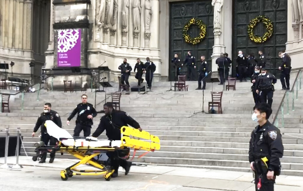 Empleados médicos llevan una camilla al lugar de un tiroteo en la catedral de San Juan el Divino, el domingo 13 de diciembre de 2020. (AP)