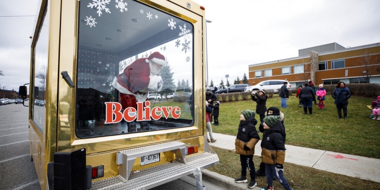 Un hombre vestido de Santa Claus saluda a los niños desde una vitrina móvil en Vaughan, Ontario, Canadá, el 13 de diciembre de 2020. (AP)
