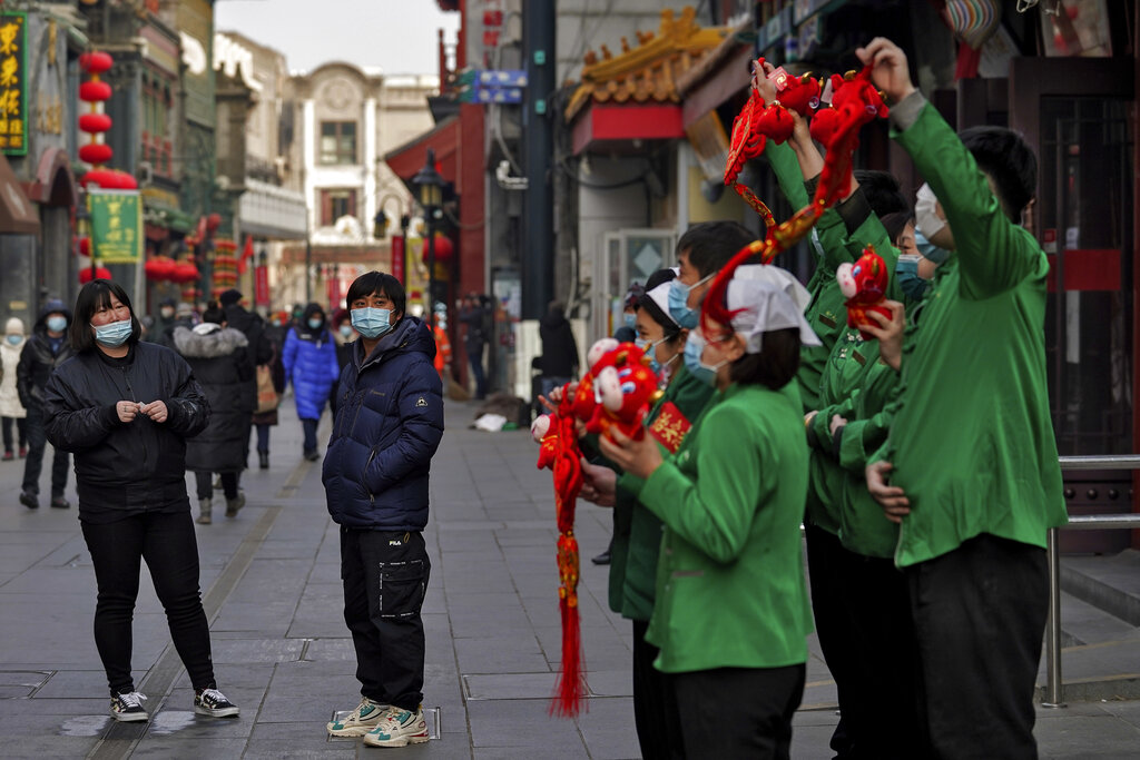 Unas personas con cubrebocas para protegerse del coronavirus cerca de la calle de comercios Qianmen, un sitio turístico en Beijing, China, el 31 de enero de 2021. (AP)