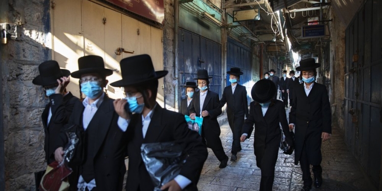 Un grupo de jóvenes judíos ultraortodoxos usa cubrebocas en la vieja ciudad de Jerusalén. AP