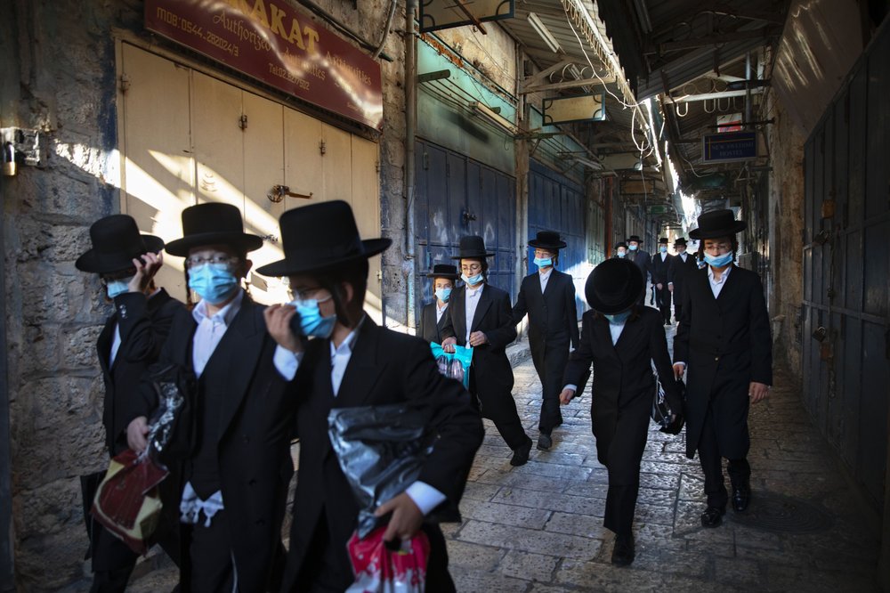Un grupo de jóvenes judíos ultraortodoxos usa cubrebocas en la vieja ciudad de Jerusalén. AP