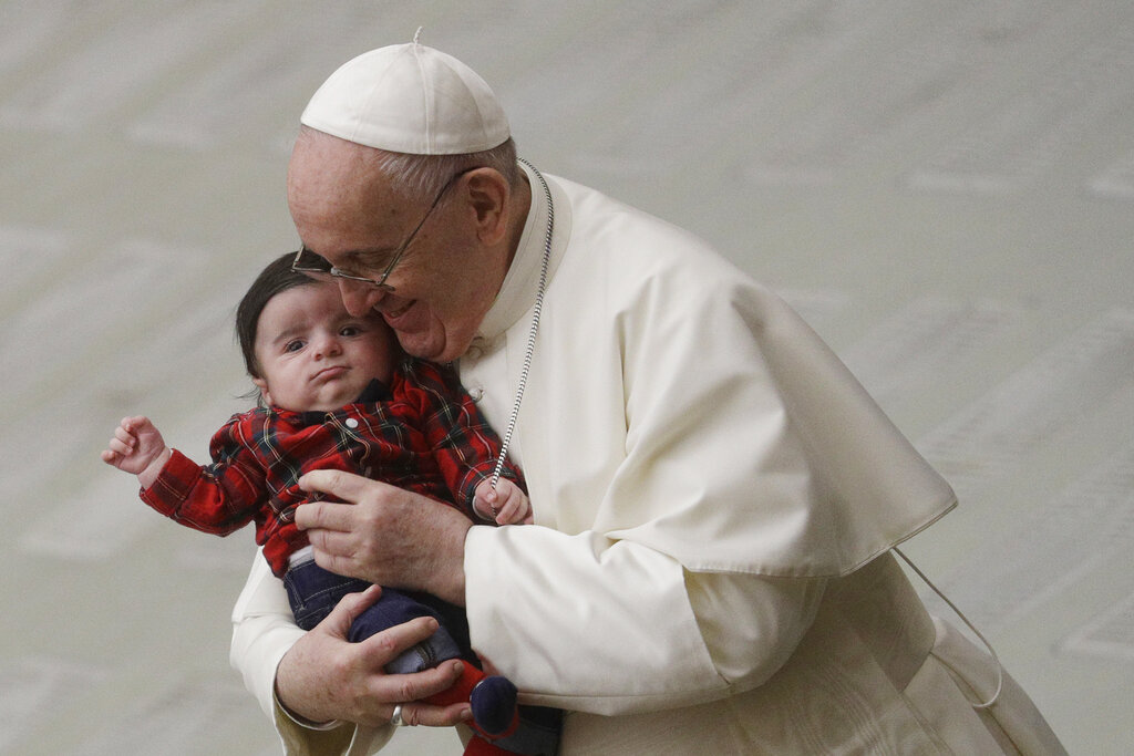 El papa Francisco carga a un bebé mientras convive con empleados del Vaticano, en el salón Pablo VI, el 21 de diciembre de 2020. (AP)
