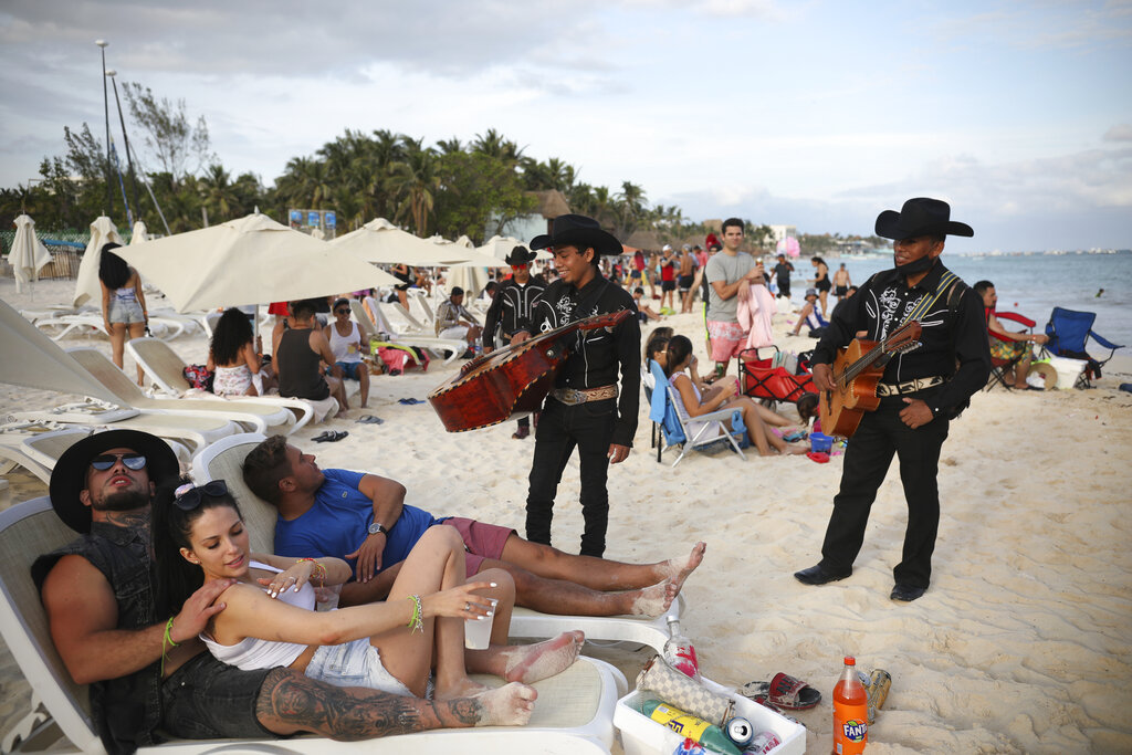 El dúo Los Compas ofrece sus servicios a turistas en la playa Mamitas de Playa del Carmen, en México, el 5 de enero del 2021. (AP)