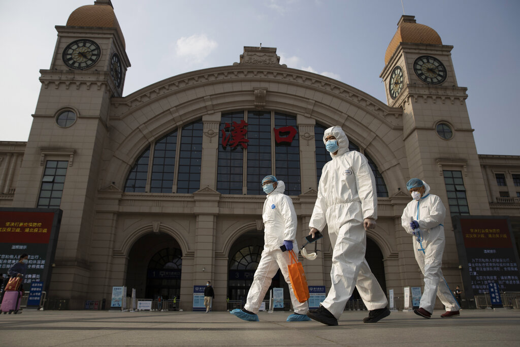 Trabajadores vestidos con equipos de protección por el coronavirus pasan delante de la estación de tren de Hankou, en Wuhan, provincia de Hubei, China, el 7 de abril de 2020. (AP)