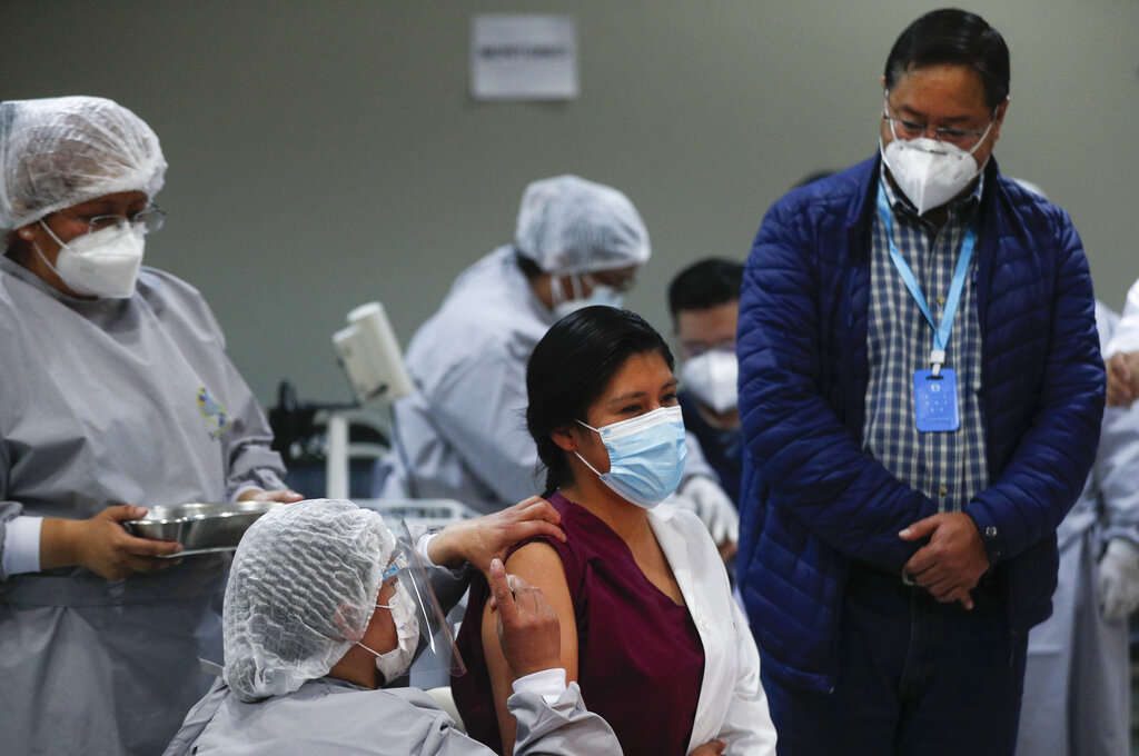 El presidente boliviano Luis Arce, a la derecha, observa cómo una trabajadora de la salud recibe una dosis de la vacuna rusa Sputnik V COVID-19 en el Hospital Del Norte en El Alto, Bolivia, el sábado 30 de enero de 2021. (AP)