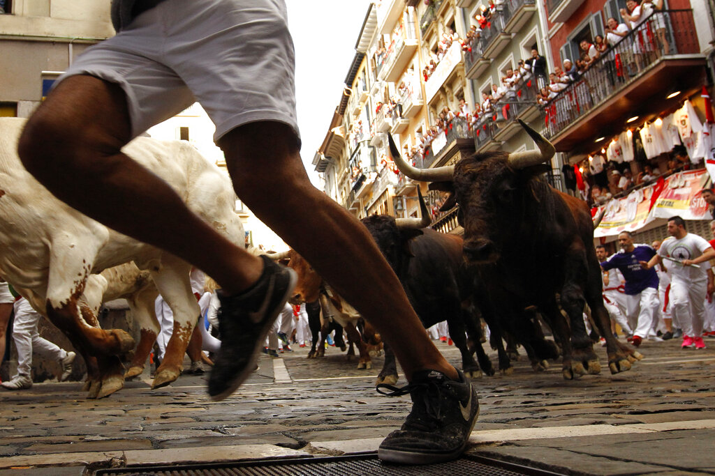 Juerguistas corren junto a toros del rancho Cebada Gago en el festival de San Fermín, en Pamplona, España, el lunes 8 de julio de 2019. (AP Foto/Alvaro Barrientos)