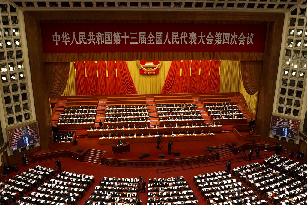 La sesión de apertura del Congreso Nacional Popular de China, con delegados en el lugar y pantallas que muestran al presidente de China, Xi Jinping, en el Gran Salón del Pueblo de Beijing, el viernes 5 de marzo de 2021. (AP Foto/Andy Wong)