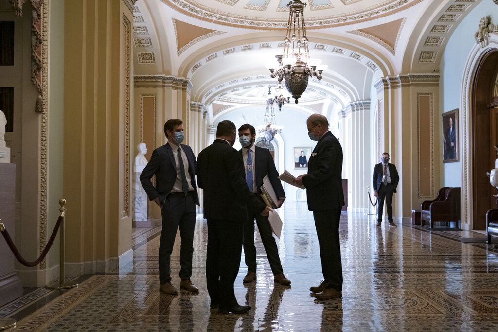 Personal del Congreso espera en un ornamentado pasillo en el exterior de la cámara del Senado durante una demora en los preparativos para acordar un paquete de ayudas por el COVID-19, en el Capitol, Washington, el 5 de marzo de 2021. (AP Foto/J. Scott Applewhite)