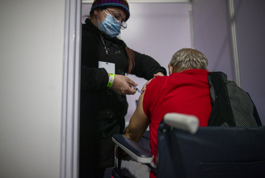 Un hombre recibe la segunda dosis de la vacuna Sinovac contra el COVID-19 en un centro de vacunación en el Estadio Bicentenario en Santiago de Chile, el jueves 18 de marzo de 2021. En medio de la exitosa campaña de inmunización, el país sudamericano enfrenta un repunte importante en los contagios. (AP Foto/Esteban Félix)