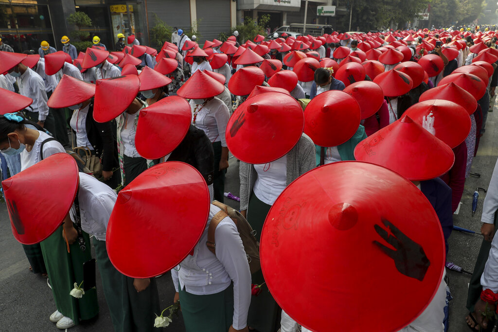 Maestros de escuela contrarios al golpe de Estado, vestidos con sus uniformes y el sombrero tradicional birmano _ que lleva pintado un gesto con tres dedos en alto _, participan en una protesta en Mandalay, Myanmar, el 3 de marzo de 2021. (AP Foto)