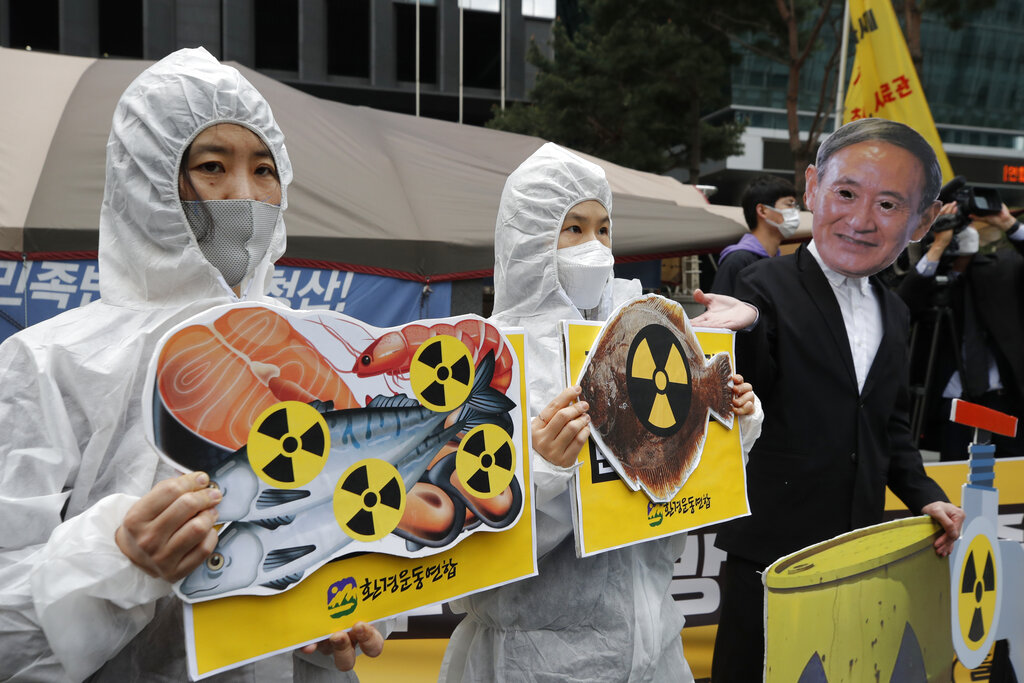 Activistas ambientales con una máscara del primer ministro japonés Yoshihide Suga protestan por la decisión de Japón de verter al mar agua de la planta nuclear de Fukushima, cerca de la embajada japonesa en Seúl, Corea del Sur, el martes 13 de abril de 2021. (Foto AP/Lee Jin-man)