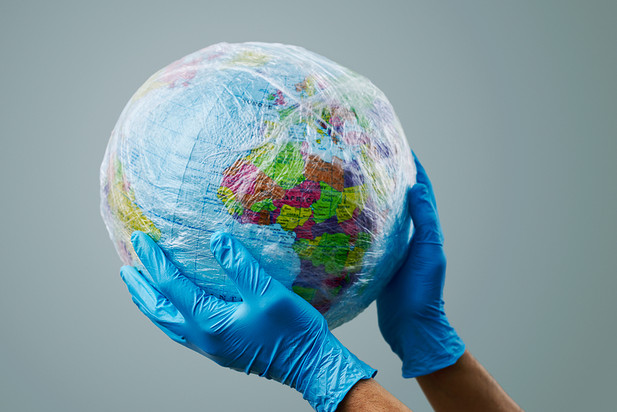 a doctor man wearing blue surgical gloves holding a world globe wrapped in plastic, depicting the plastic contamination or the protection against the epidemic infectious diseases or the air pollution