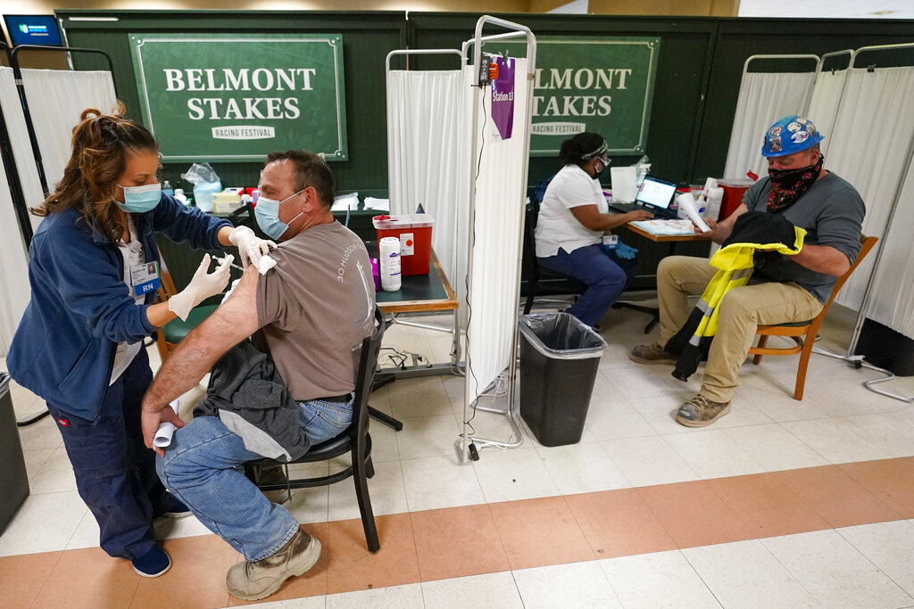 Una enfermera aplica la primera dosis de la vacuna de Pfizer contra el coronavirus a trabajadores de la industria metalúrgica, en un centro de vacunación en Belmont Park, el miércoles 14 de abril de 2021, en Elmont, Nueva York. (AP Foto/Mary Altaffer)