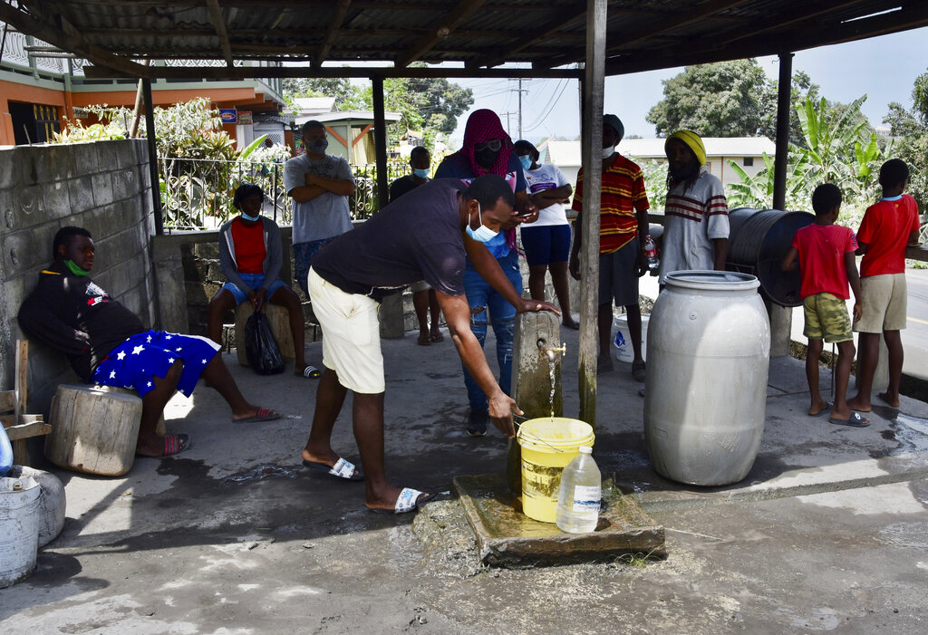Personas recogen agua no contaminada con ceniza volcánica después de la erupción del volcán La Soufrière, en Wallibou, en la parte occidental de la isla caribeña de San Vicente, el lunes 12 de abril de 2021. (AP Foto/Orvil Samuel)