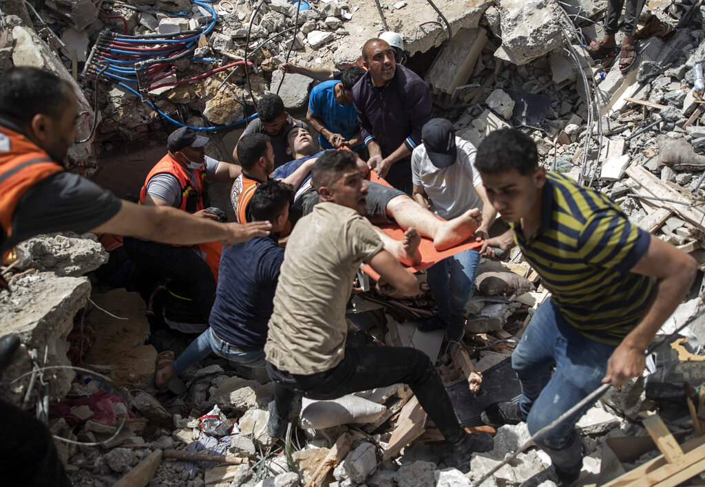 Palestinos sacan a un sobreviviente entre los escombros de un edificio residencial destruido por un bombardeo de Israel en Gaza, el 16 de mayo de 2021. (AP Foto/Khalil Hamra)