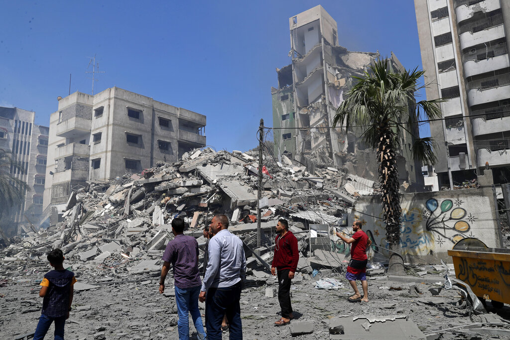 Unas personas observan los escombros del edificio residencial Yazegi destruido por un bombardeo de Israel en Gaza, el 16 de mayo de 2021. (AP Foto/Adel Hana)