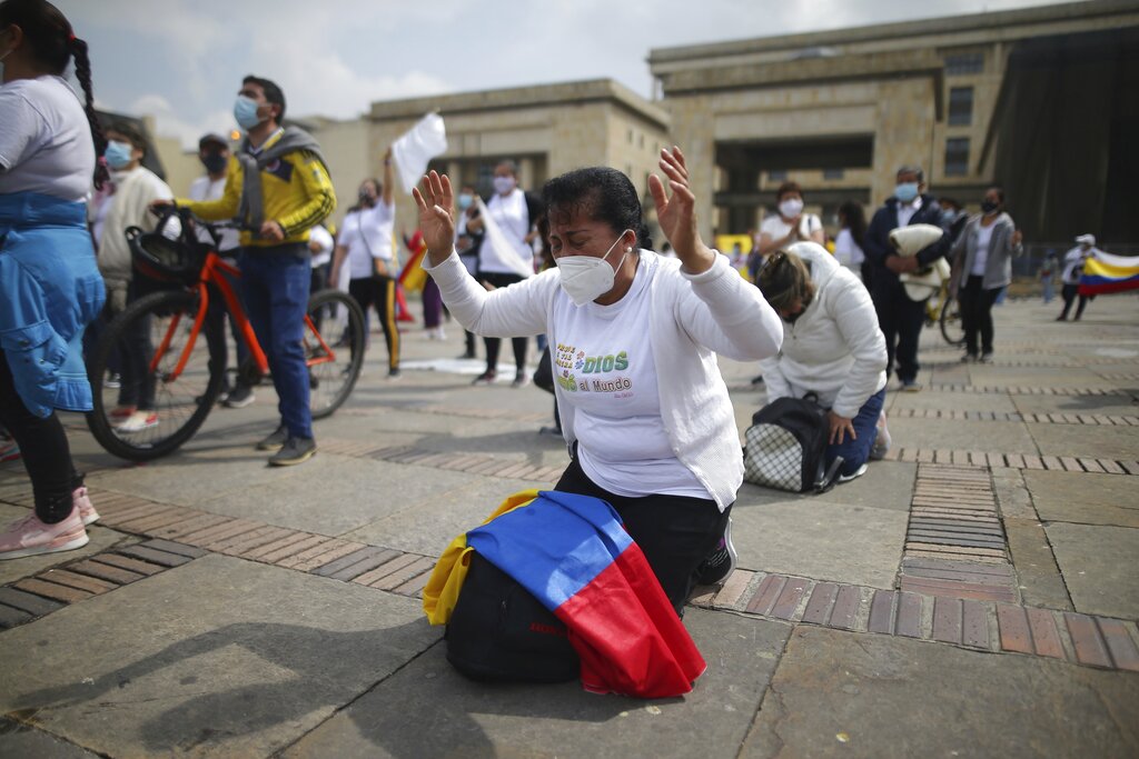 Cristianos se arrodillan para pedir que pare la violencia durante las protestas en contra del gobierno en la plaza Bolívar en Bogotá, Colombia, el sábado 8 de mayo de 2021. (AP Foto/Iván Valencia)