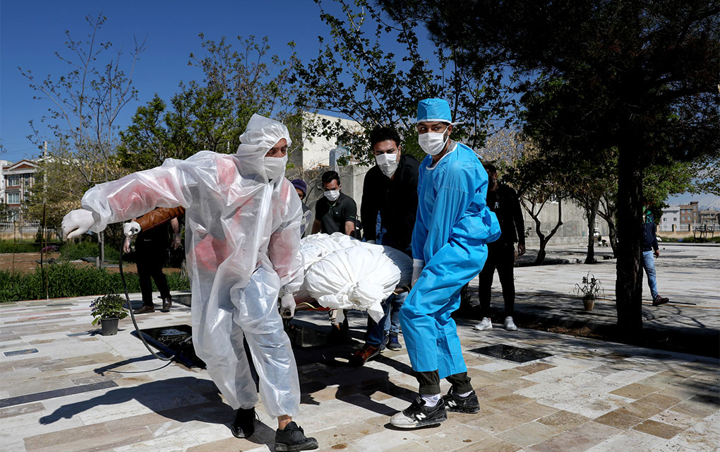 People wearing protective clothing carry the body of a victim who died after being infected with the new coronavirus at a cemetery just outside Tehran, Iran, Monday, March 30, 2020. The new coronavirus causes mild or moderate symptoms for most people, but for some, especially older adults and people with existing health problems, it can cause more severe illness or death. (AP Photo/Ebrahim Noroozi)