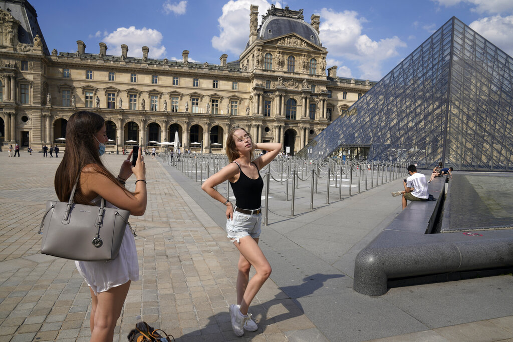 La alemana Paula Wei, derecha, es fotografiada el miércoles 9 de junio de 2021 por una amiga francesa frente al museo del Louvre, en París. (AP Foto/Francois Mori)