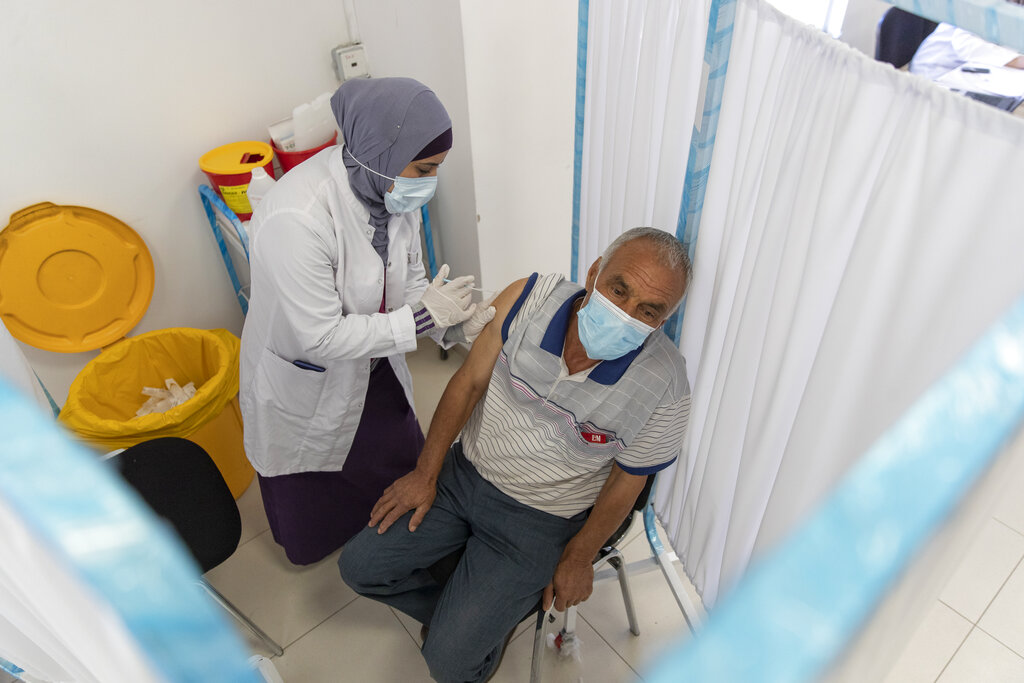 Una trabajadora sanitaria administra una dosis de la vacuna contra el COVID-19 desarrollada por AstraZeneca y la Universidad de Oxford a un palestino durante una campaña de vacunación, en Ramala, Cisjordania, el 6 de junio de 2021. (AP Foto/Nasser Nasser)
