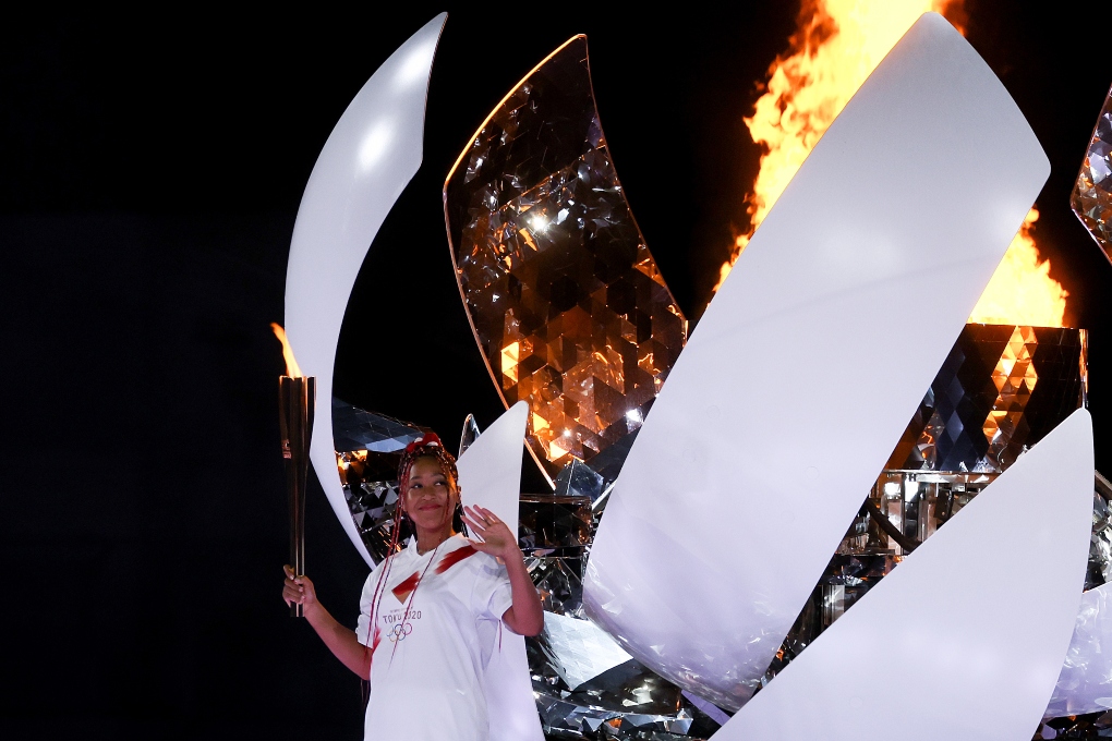 Naomi Osaka stands with a torch after lighting the Olympic flame at the Olympic Stadium during the opening ceremony of the postponed 2020 Tokyo Olympics in Tokyo on Friday, July 23, 2021. Multiracial athletes like Osaka and Rui Hachimura are helping to redefine what it means to be Japanese. But they are often still seen as outsiders. (Hiroko Masuike/The New York Times)