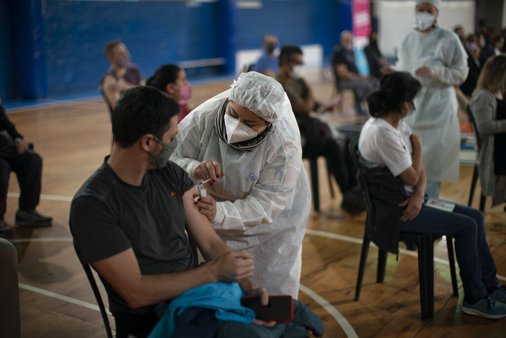 La supervisora de enfermería Paola Almiron inocula a un hombre con una dosis de la vacuna de Sinopharm contra el COVID-19 en un gimnasio en las afueras de Buenos Aires, el viernes 9 de julio de 2021. (AP Foto/Victor R. Caivano)
