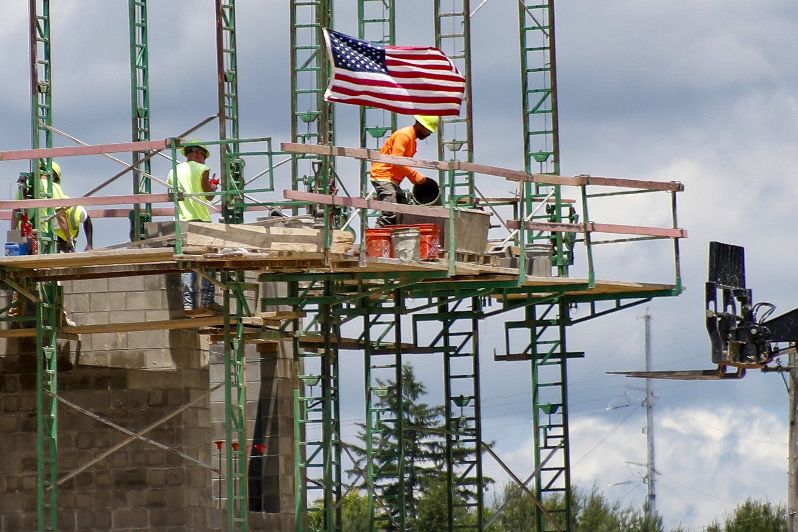 FILE - In this June 11, 2020, file photo workers on scaffolding lay blocks on one of the larger buildings at a development site where various residential units and commercial sites are under construction in Cranberry Township, Butler County, Pa. Eighty-five percent of Democrats call economic conditions “poor,” while 65% of Republicans describe them as “good,” according to a new survey by The Associated Press-NORC Center for Public Affairs Research. (AP Photo/Keith Srakocic, File)