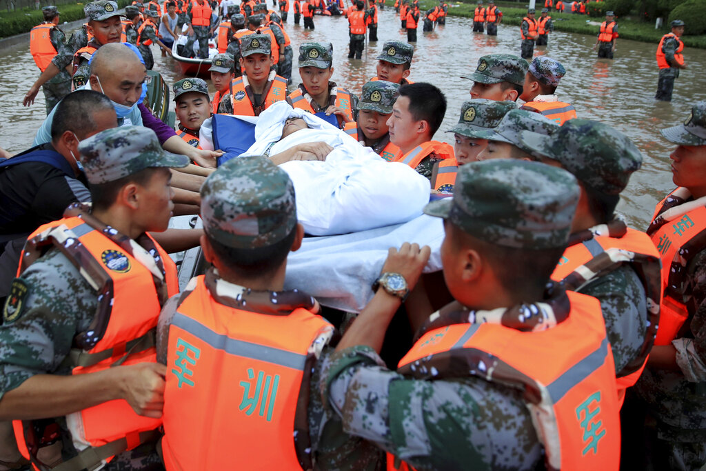 Soldados del ejército chino desalojan a pacientes de un hospital donde alrededor de 3.000 personas quedaron atrapados por las inundaciones en Zhengzhou, en la provincia de Henan, en el centro de China, el 22 de julio de 2021. (Chinatopix Via AP)