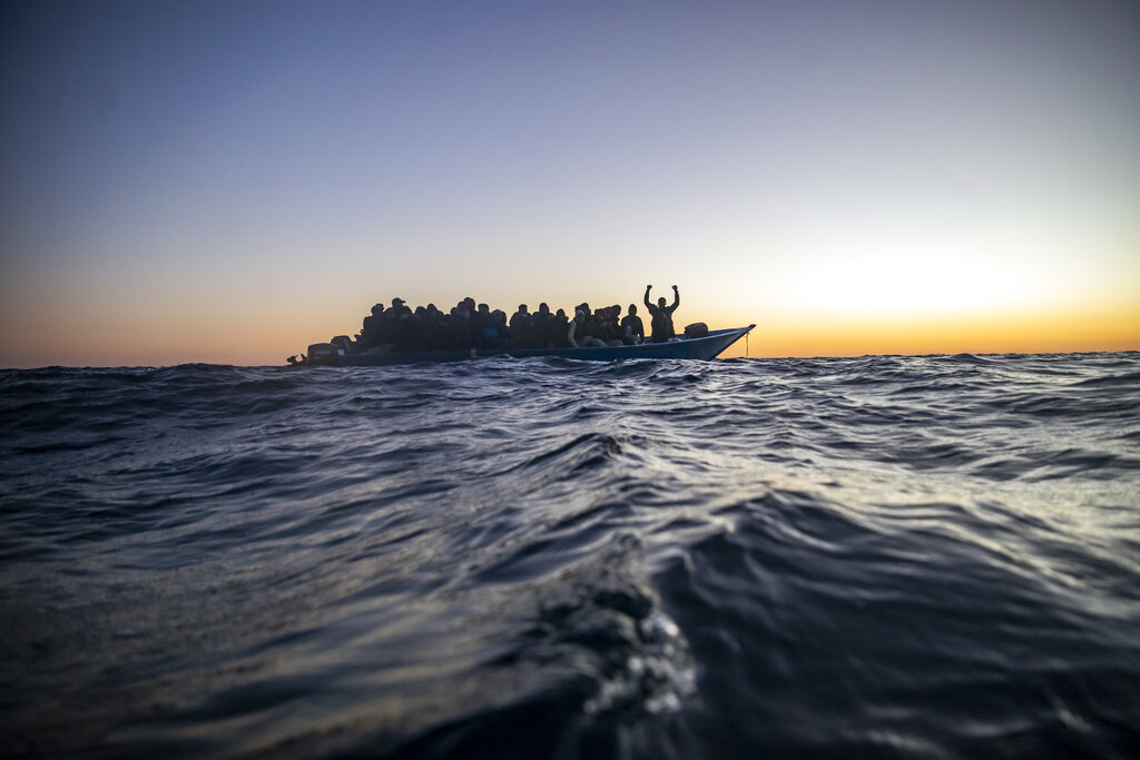 En esta imagen del 12 de febrero de 2021, migrantes y refugiados de varios países esperan ayuda a bordo de una hacinada embarcación de madera, mientras trabajadores de ayuda de la ONG española Open Arms se acercan a ellos en aguas internacionales del Mar Mediterráneo. (AP Foto/Bruno Thevenin, Archivo)