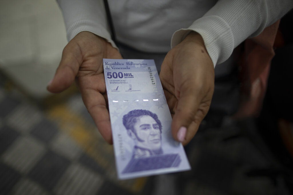 ARCHIVO - En esta fotografía de archivo del 16 de marzo de 2021, una mujer muestra un nuevo billete de 500.000 bolívares luego de retirarlo de un banco en Caracas, Venezuela. El 5 de agosto el Banco Central de Venezuela anunció que eliminará seis ceros a la moneda a partir del 1 de octubre. (AP Foto/Ariana Cubillos, Archivo)