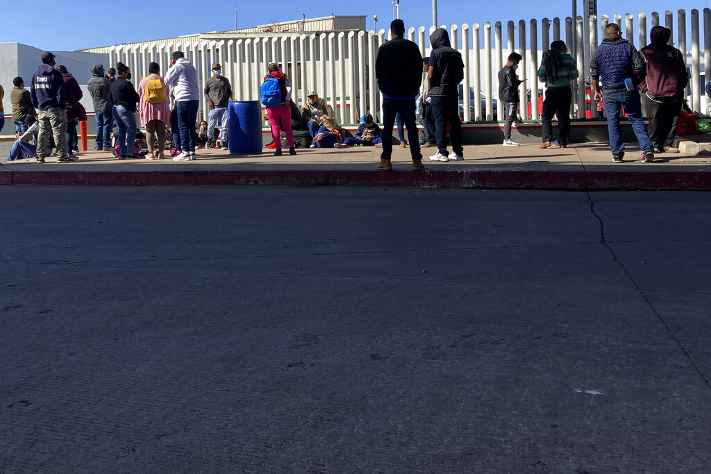 En esta imagen del miércoles 17 de febrero de 2021, migrantes en espera de noticias en un cruce fronterizo en Tijuana, México. (AP Foto/Elliot Spagat)