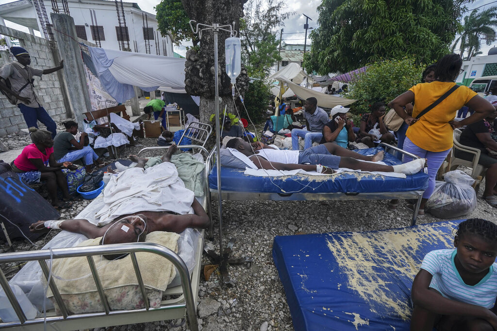 Gente herida descansa en camas en el exterior del hospital Immaculée Conception en Les Cayes, Haití, el 16 de agosto de 2021, dos días después de un sismo de magnitud 7,2 que remeció el suroeste del país. (AP Foto/Fernando Llano)