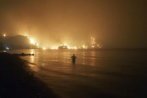 Un hombre contempla desde la playa las llamas de un incendio forestal que se le acerca en la aldea de Limni, Grecia. (AP)