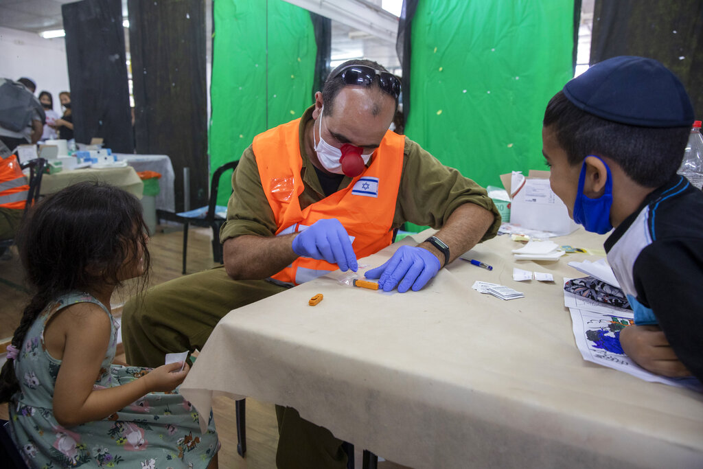 Un soldado israelí realiza una prueba de anticuerpos a una niña en Hadera el 23 de agosto del 2021.  (AP Foto/Ariel Schalit)